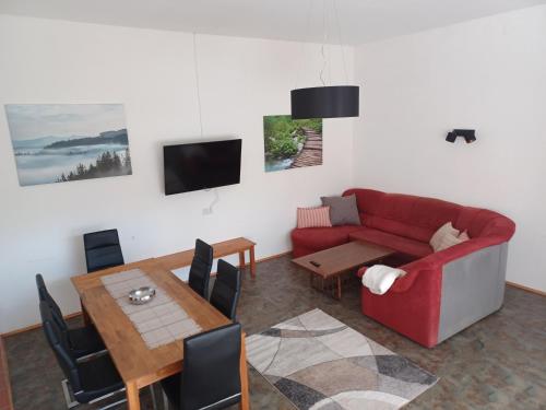 a living room with a red couch and a table at Ferienwohnungen und Appartements im idyllischen Vierkanthof, Gruppenurlaube in Loipersdorf bei Fürstenfeld
