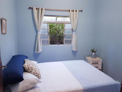 a blue bedroom with a bed and a window at Casa com piscina próxima a pontos turísticos in São Lourenço