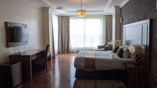 a bedroom with a bed and a desk and a television at Fully Furnished Two Bedroom along TRM Drive in Nairobi