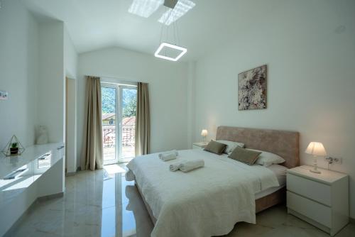 a white bedroom with a large bed and a window at The Golden Luxury Apartments in Kotor
