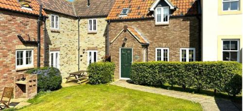 a brick house with a green door and a yard at Dream Weaver 2 Bedroomed cottage on The Bay, Filey with on-site gym and swimming pool in Filey
