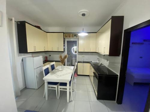 a kitchen with a white table and a white refrigerator at Vila Reni Risi in Ksamil