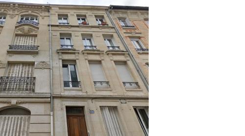 a tall building with windows and a fire ladder at L'Instant Rémois - Hypercentre Boulingrin in Reims
