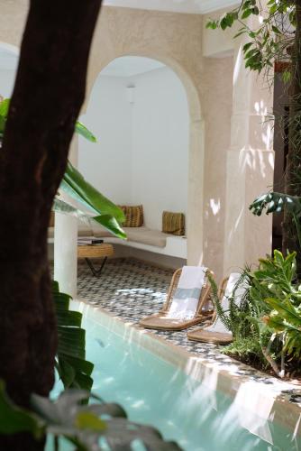 una piscina con sedia e divano in una stanza di Riad L'Atelier a Marrakech