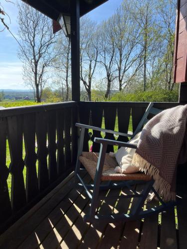 a wooden bench on a deck with a view of a field at Koselig hytte på eget tun med varmtvanns utedusj in Ås
