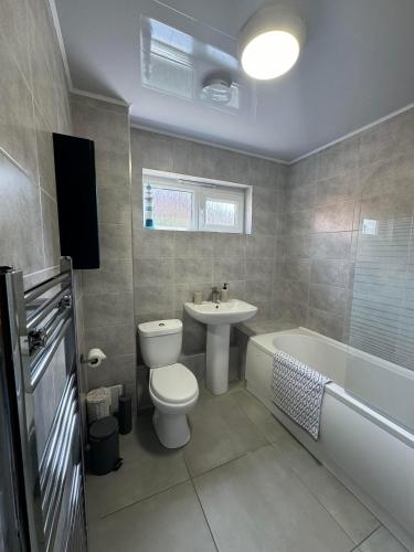 a bathroom with a toilet and a sink and a bath tub at Stylish apartment in The City Centre in Kingsthorpe
