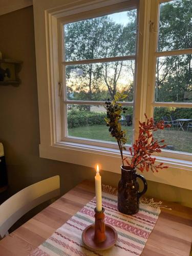a candle sitting on a table next to a window at Koselig hytte på eget tun med varmtvanns utedusj in Ås