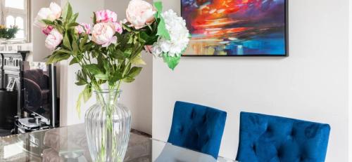 a vase of pink flowers sitting on a glass table at Stunning sea views from rooms and terraces in Leigh-on-Sea