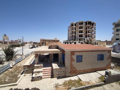 a house under construction with a tall building in the background at Ageeba Beach Challet 17 in Marsa Matruh