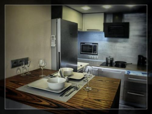 a kitchen with a wooden table with bowls and wine glasses at Vision Luxury Apartment Rynek in Wrocław