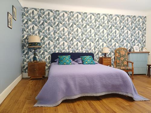 a bedroom with a bed with a purple bedspread at Maison Violette en Berry - chambres d'hôtes vintage face au marché d'Aigurande in Aigurande