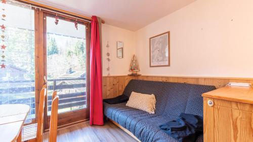 un salon avec un canapé bleu et une fenêtre dans l'établissement Studio très agréable Morillon 1100 - 2/4 pers, à Morillon