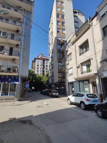 a city street with cars parked in front of buildings at "Lemi - King of Rajiceva st" in Niš