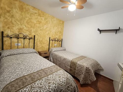 a bedroom with two beds and a ceiling fan at Casa Las Peñuelas in Priego
