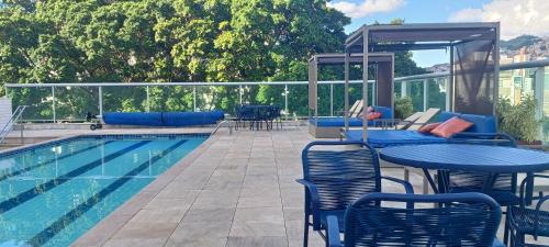 a swimming pool with tables and chairs next to a swimming pool at Suíte Alto Afonso Pena in Belo Horizonte
