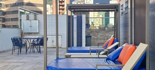 a balcony with blue and orange pillows and a table and chairs at Suíte Alto Afonso Pena in Belo Horizonte