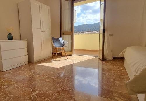 a bedroom with a chair and a bed and a window at Mare & Monti Casa Vacanze in Teulada
