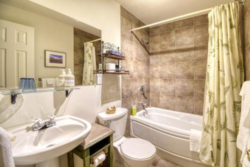 a bathroom with a sink and a tub and a toilet at Auberge Le Lupin-Self Check-in in Mont-Tremblant