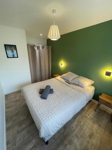 une chambre avec un lit blanc avec un mur vert dans l'établissement L'Oscar, à Clermont-Ferrand