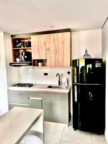 a kitchen with a black refrigerator and a sink at Apartamento Premium Sabaneta in Sabaneta
