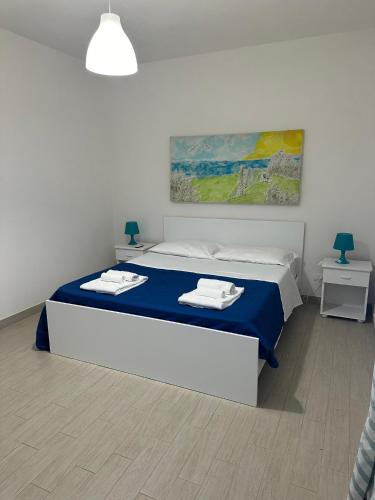 a bedroom with a bed with blue sheets and a painting at Favignana Holidays in Favignana