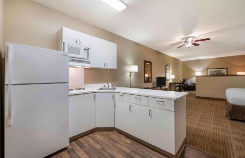a kitchen with a white refrigerator and a living room at Extended Stay America Select Suites - Peoria - North in Peoria