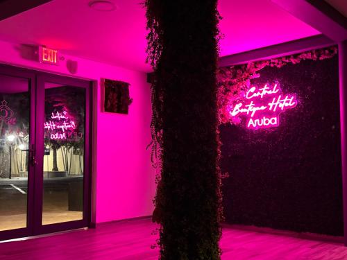 a pink room with a tree in front of a store at Central Boutique Hotel in Oranjestad