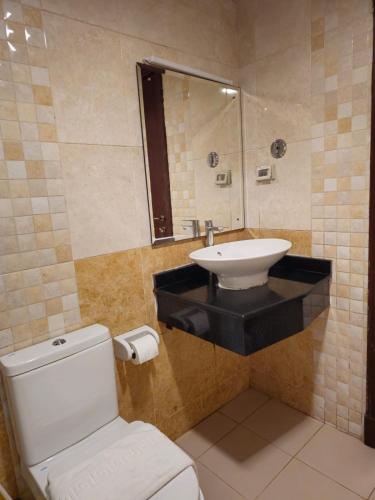 a bathroom with a white toilet and a sink at Twilight Hotel in Muscat