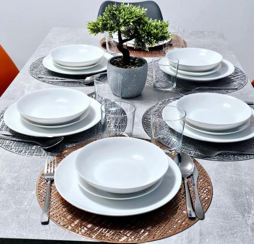 a table with white plates and forks and spoons at LushStay Telford - Families, Contractors & Group of Friends, long term stay in Telford