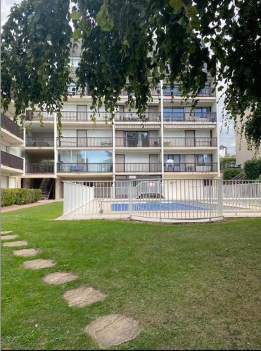 un bâtiment avec une clôture devant une cour dans l'établissement Appartement Trouville Duplex piscine chauffée, à Trouville-sur-Mer