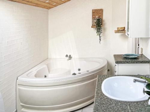 une salle de bain blanche avec une baignoire et un lavabo dans l'établissement 6 person holiday home in Hadsund, à Hadsund