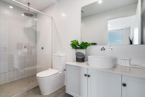 a white bathroom with a toilet and a sink at The Esplanade - Luxuriously Styled New 3 Bed Apt in Moana