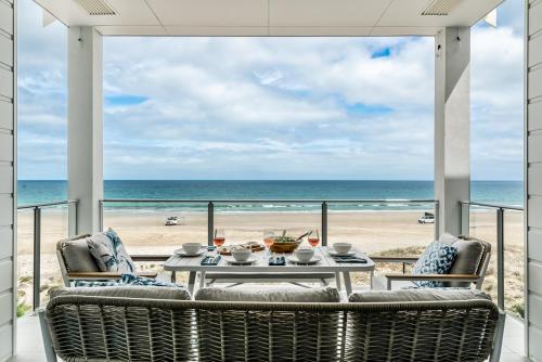 a dining room with a view of the beach at The Esplanade - Luxuriously Styled New 3 Bed Apt in Moana