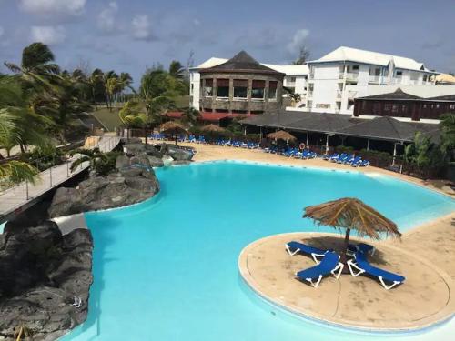a large swimming pool with chairs and an umbrella at Le MANGANAO in Saint-François