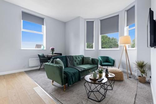 a living room with a green couch and windows at Modern Apartment Free Parking Double Bed Suite 5 in Nottingham