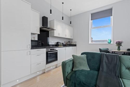 a kitchen with white cabinets and a green couch at Modern Apartment Free Parking Double Bed Suite 5 in Nottingham