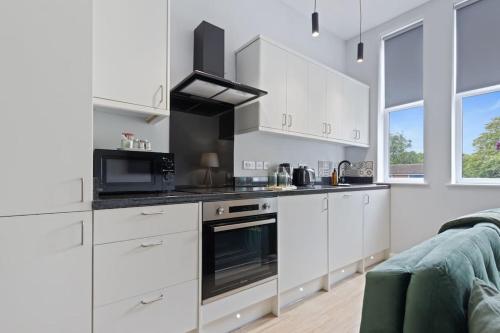 a kitchen with white cabinets and a stove top oven at Modern Apartment King with Free Parking Suite 6 in Nottingham