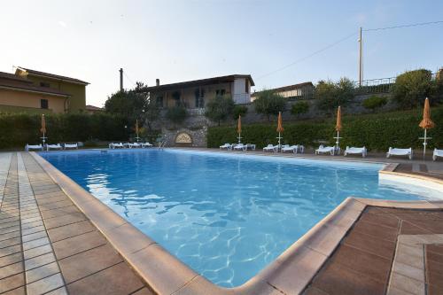 a large swimming pool with chairs and a building at Locanda La Gozzetta in Santa Luce