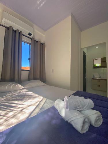 a bedroom with a bed with towels on it at Suítes Preguiça in Sao Jorge