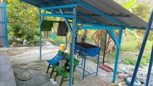 a blue shed with a bucket and chairs under it at Teratak Cikgu Roomstay in Kampong Bukit Batu Kawi