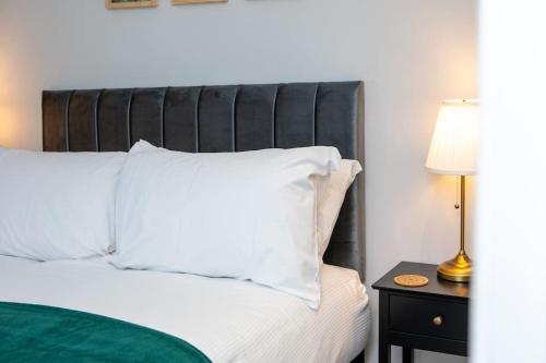 a bed with a black headboard and a table with a lamp at Modern Apartment Spacious Double Bed Off Road Parking Suite 8 in Nottingham