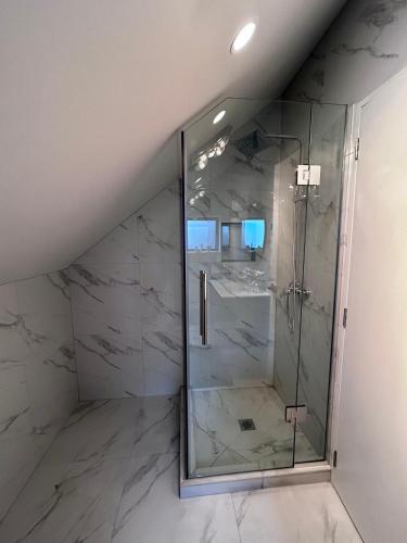 a bathroom with a shower with a glass door at Cozy Top-Floor Stay with Private Bathrooms and Free Parking in Auckland