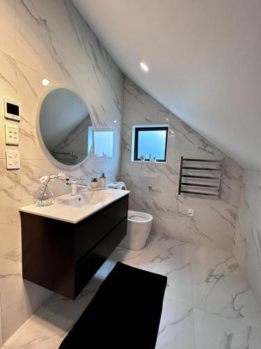 a bathroom with a sink and a mirror at Cozy Top-Floor Stay with Private Bathrooms and Free Parking in Auckland