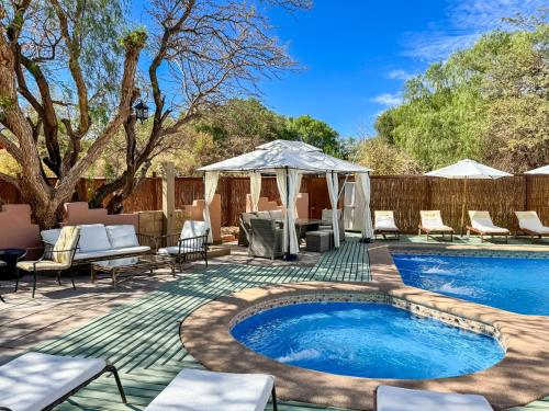 a patio with a swimming pool with chairs and a gazebo at Lodge Ancar Atacama in San Pedro de Atacama