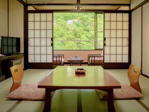a room with a table and chairs and a window at Issinkan in Nikko