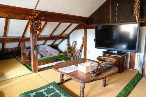 a living room with a tv and a coffee table at スキー場まで15分ー最大10人ーお餅つきー流しそうめんー花火ー五右衛門風呂ー心と身体が元気になる古民家民泊ーオモテナシロッジ悠遊 in Nakafurano