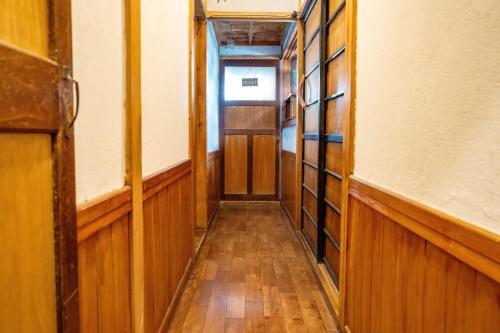 an empty hallway with wood paneling and an open door at スキー場まで15分ー最大10人ーお餅つきー流しそうめんー花火ー五右衛門風呂ー心と身体が元気になる古民家民泊ーオモテナシロッジ悠遊 in Nakafurano