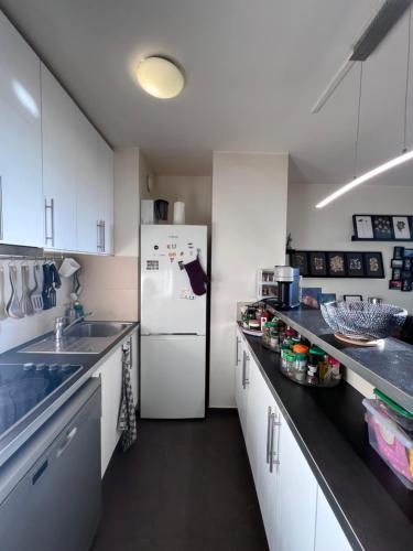 une cuisine avec des armoires blanches et un réfrigérateur blanc dans l'établissement Tour Reflet Paris 15, A cozy and welcoming home, just like your own, à Paris