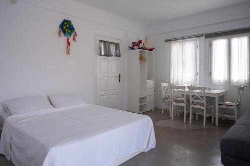 a white bedroom with a bed and a table at Kyon Beach Suites Kythnos in Kanala