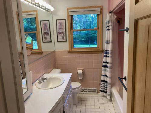 Un baño con lavabo, inodoro y ventana. en Quiet Beach Home, walk to beach access, en Plymouth